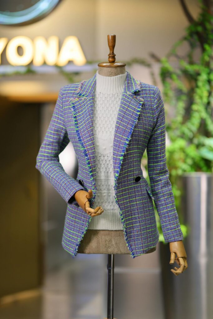 Stylish mannequin dressed in a tailored checked blazer and sweater, highlighting ladies tailoring and custom fashion design.