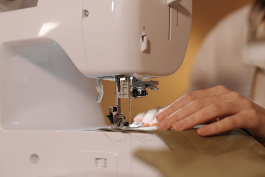 A detailed view of hands sewing fabric on a sewing machine, showcasing craftsmanship.